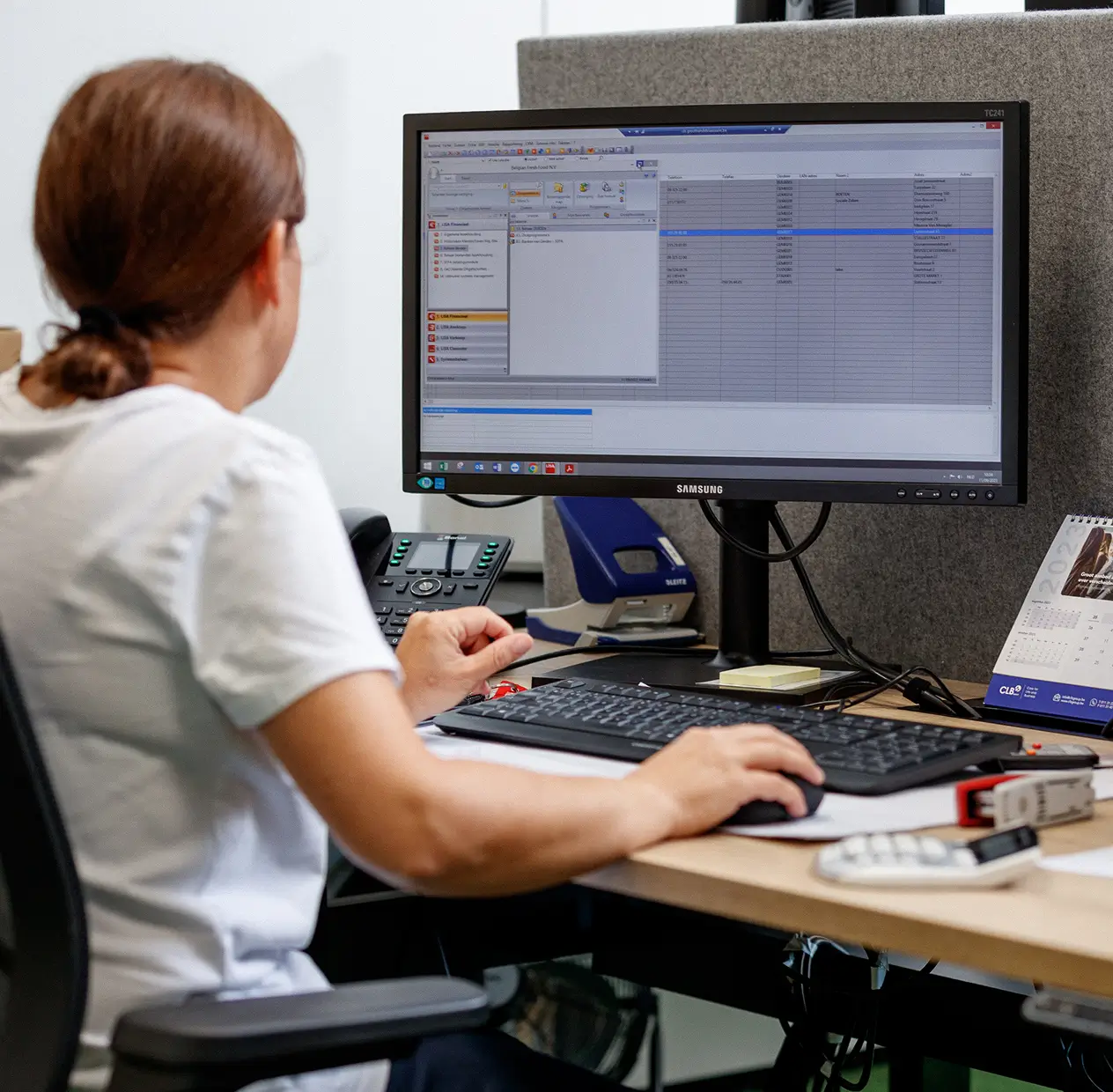 Vrouw werkt aan een bureau met een computer die een spreadsheet toont.