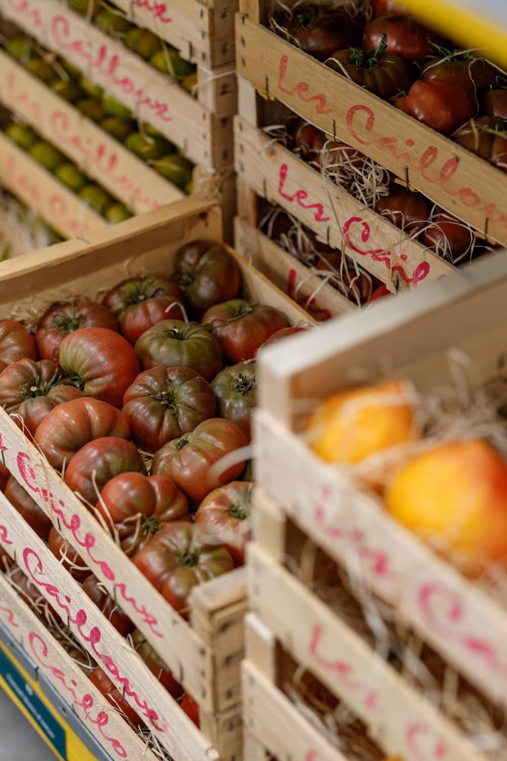 Kratten met verschillende soorten verse tomaten in een markt of winkel.