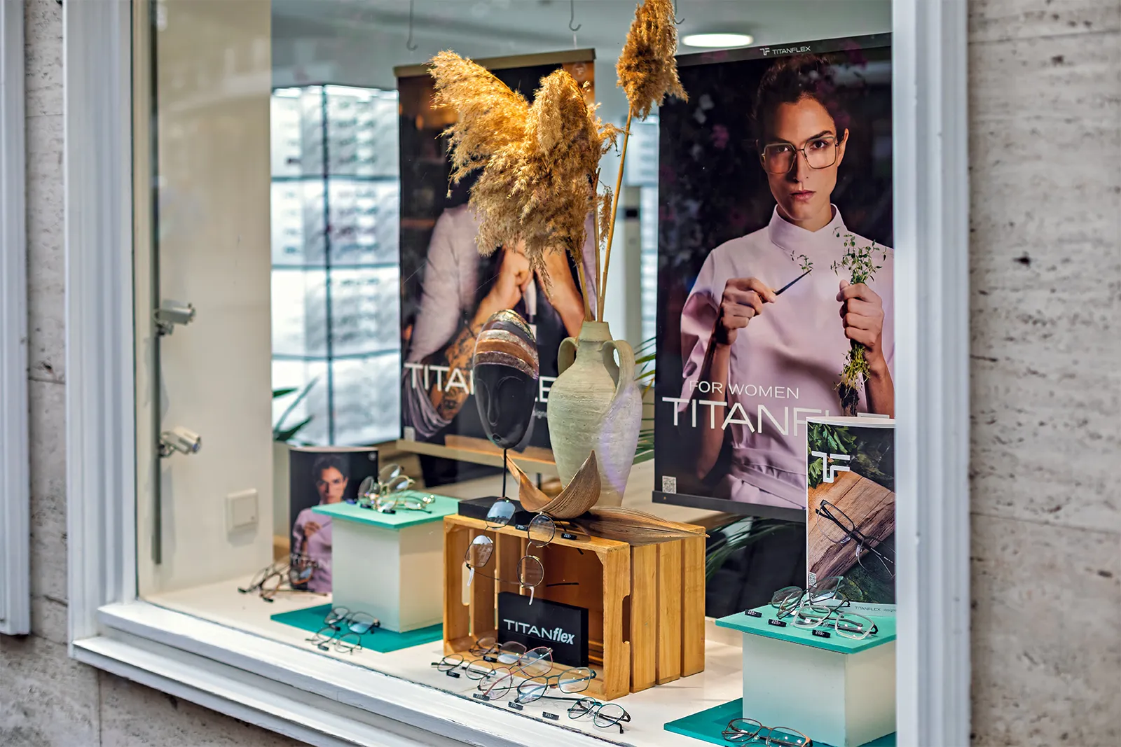 Store window displaying various eyeglasses with posters featuring models wearing Titanflex frames.