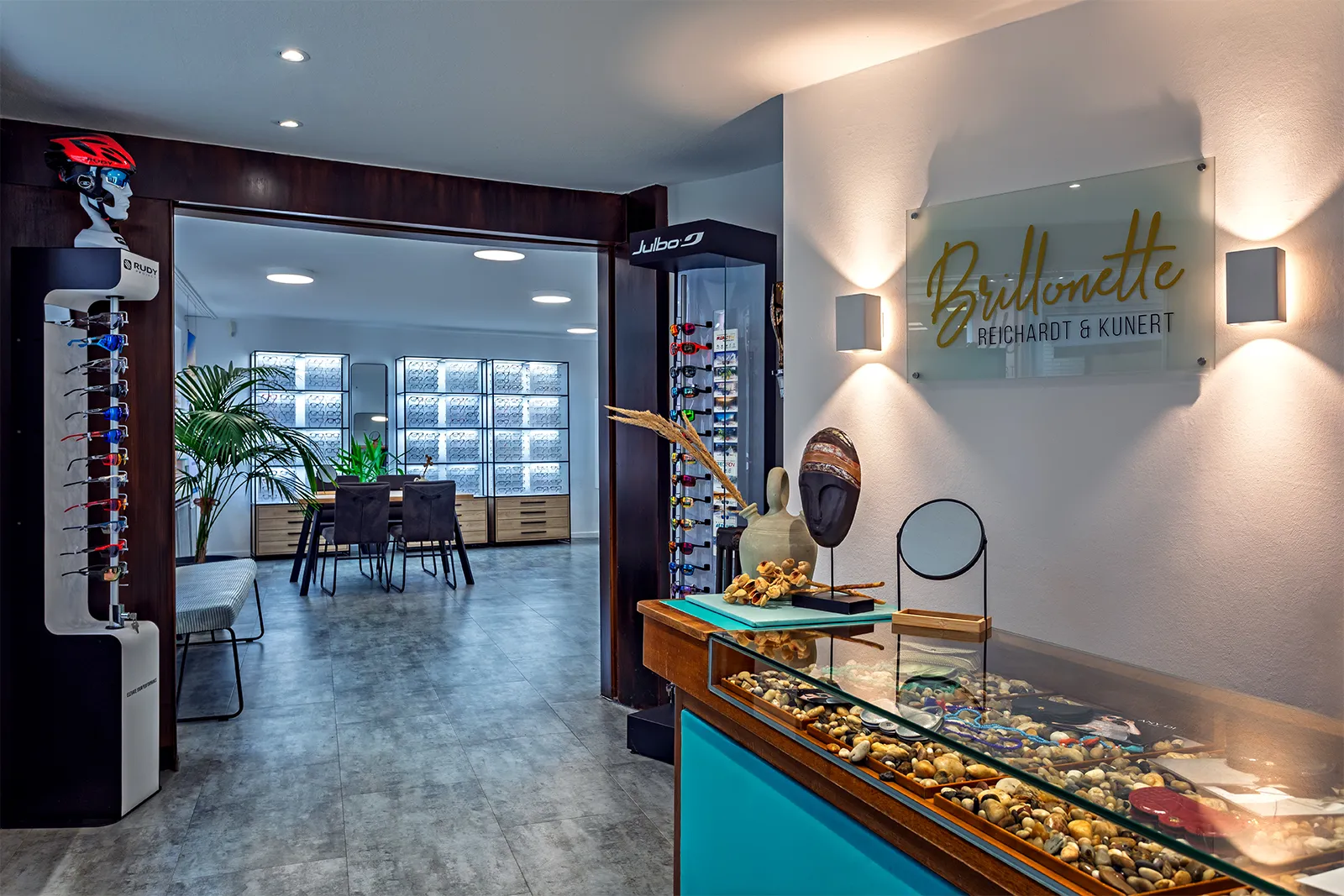 Modern optician store interior with eyeglasses displays, a consultation table, and decorative items.
