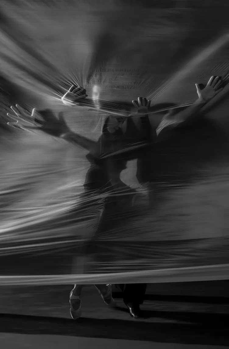 Two dancers behind a translucent sheet, their hands and bodies pressing through the fabric.