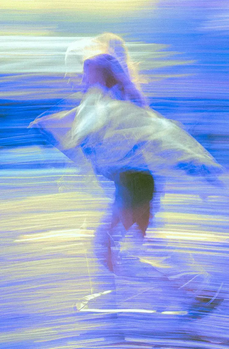 Blurred figure dancing with flowing fabric amid swirling blue and yellow light streaks.