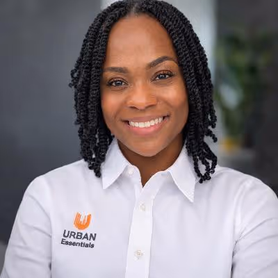 An image of a woman with a twist hairstyle and a professional, white button up that says "Urban Essentials"