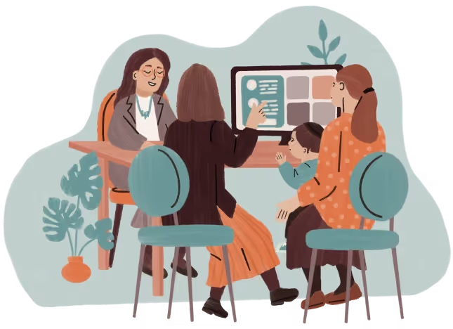 Four people sit around a table discussing something on a computer screen in an office setting.