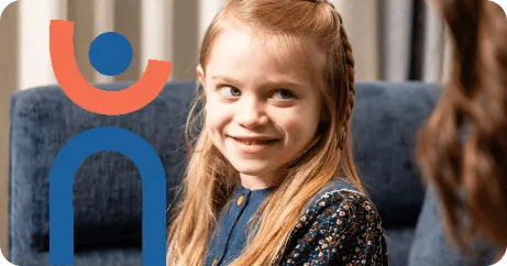Young girl with long hair smiling while sitting on a blue chair indoors.