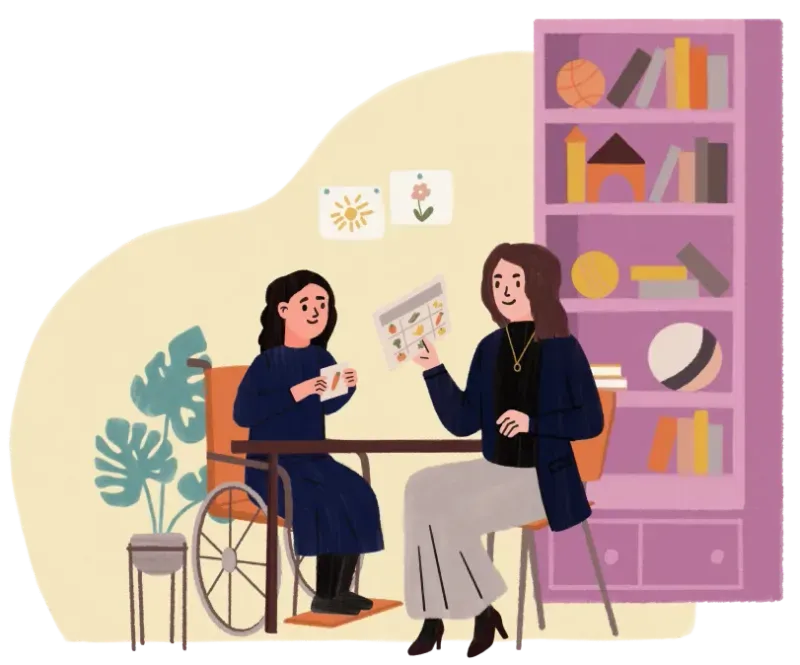 Woman showing a card with symbols to a girl in a wheelchair at a table in a cozy room.