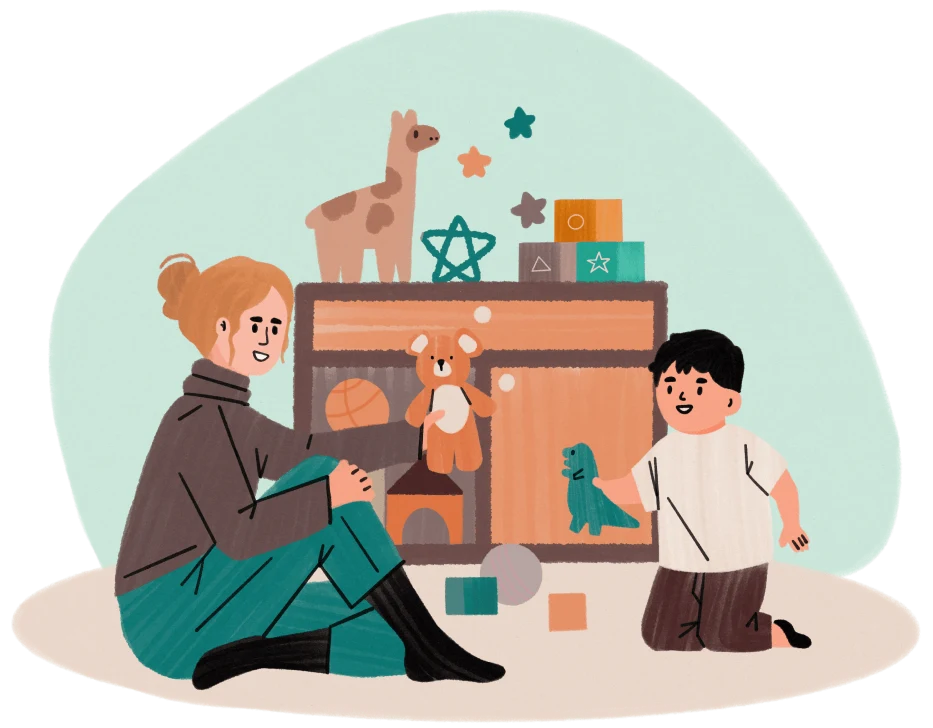 Mother sitting on floor playing with young boy surrounded by toys and stuffed animals.