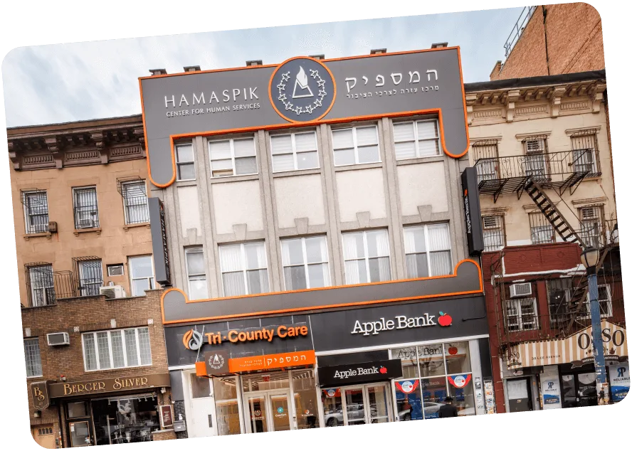 Building with signs for HAMASPIK Center, Tri-County Care, and Apple Bank in an urban street scene.