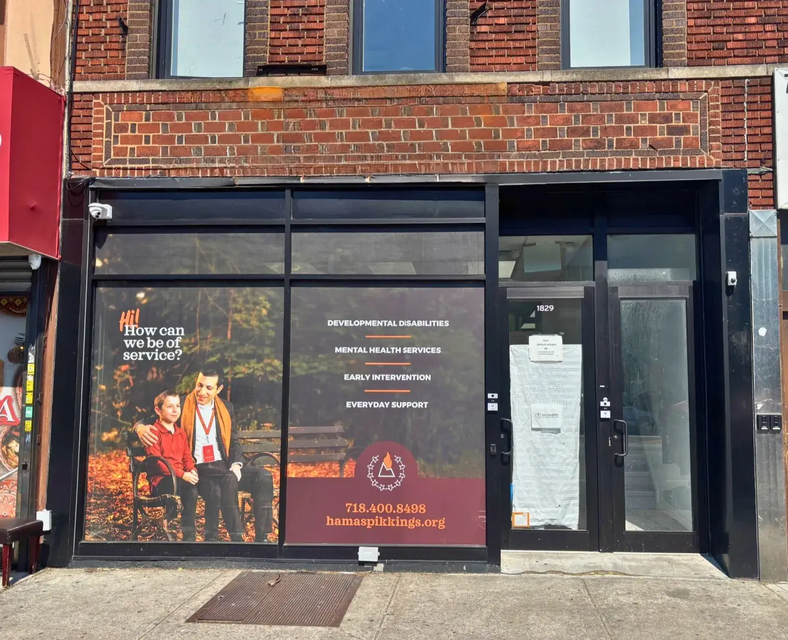 Building front with large windows showing a man and boy seated and mental health service information.