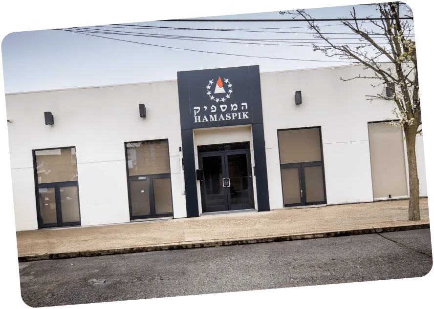 Modern white building with black framed glass doors and Hamaspik sign above entrance.