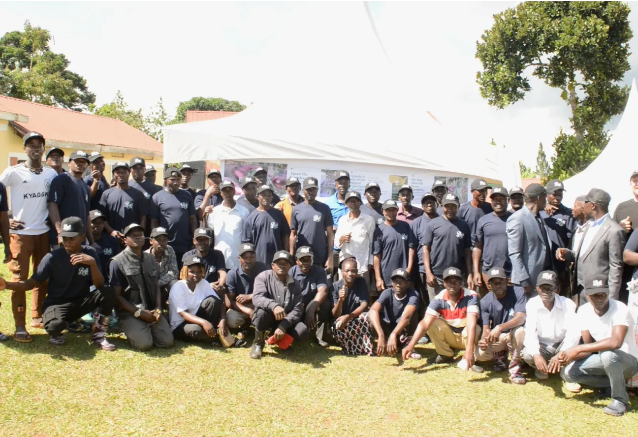 Large group of people posing outdoors in front of a tent on a sunny day.