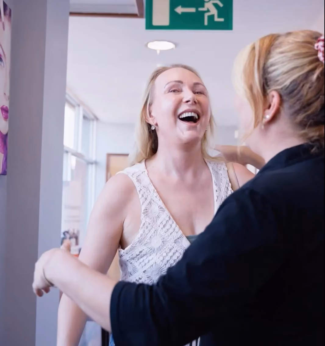 A new patient laughing as she is welcomed at the Sale Dental Spa reception desk