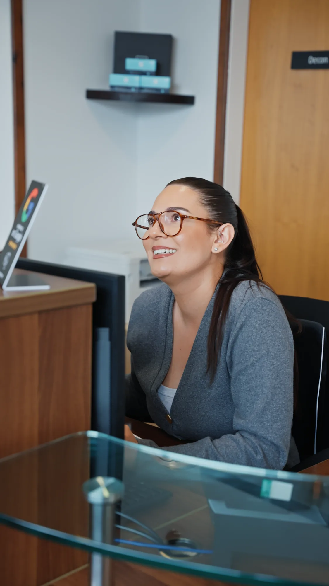 A member of the front of house team smiling at the reception desk at Sale Dental Spa