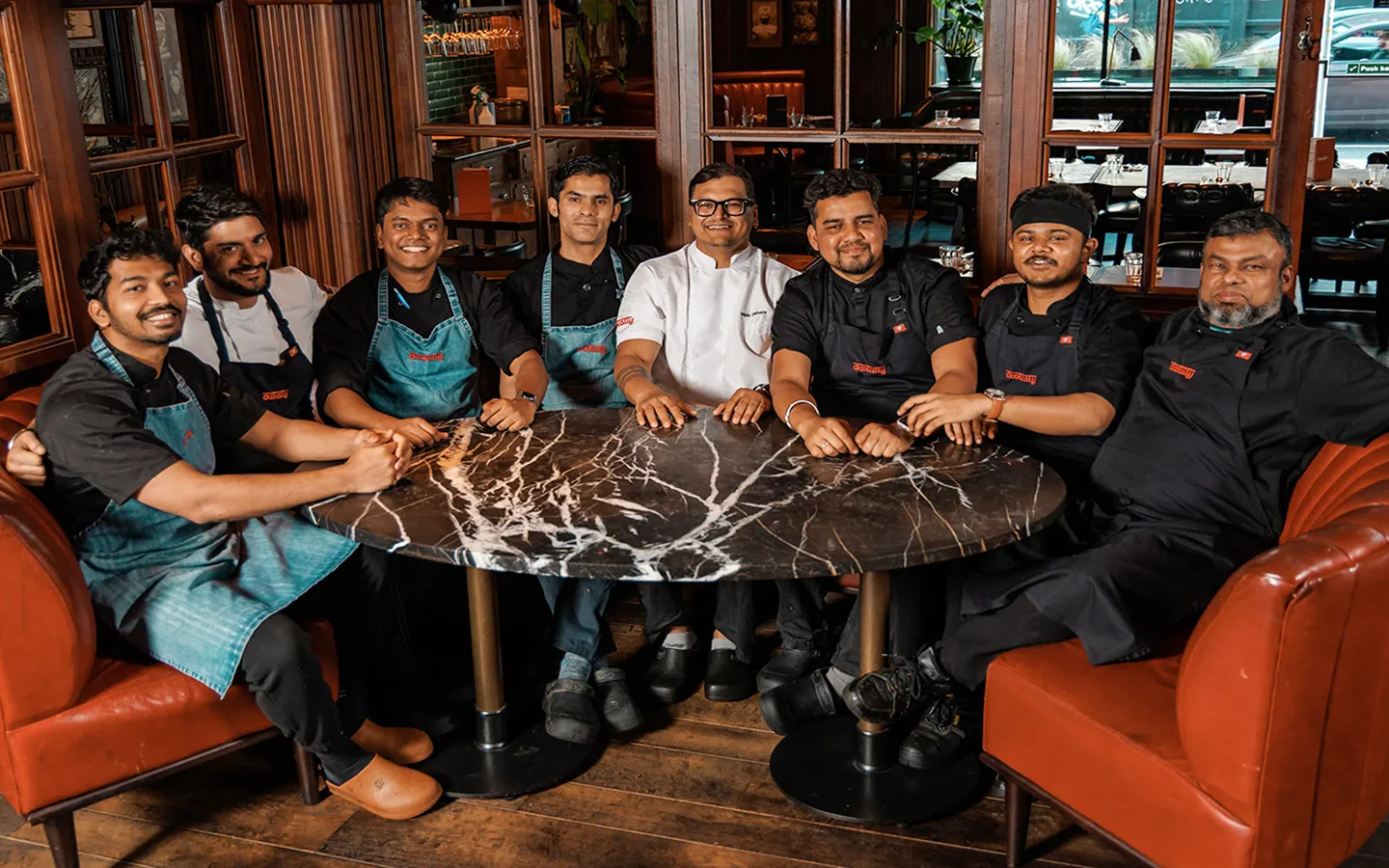 Kitchen and floor team seated around a marble table in a wood-panelled dining room