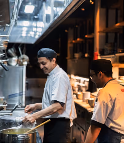 Chefs in whites working side by side on the line in an open kitchen