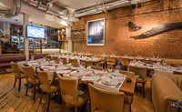 Long table set for a group dinner in an exposed-brick dining room
