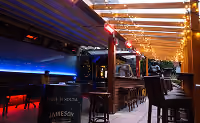 Covered terrace bar lit with string lights and blue neon at night
