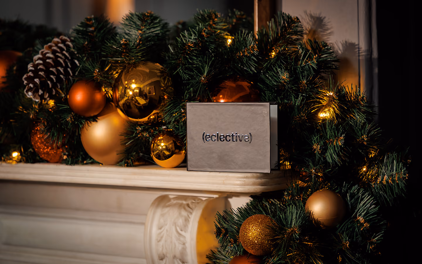 Eclective gift box on a marble mantelpiece amid a Christmas garland and gold baubles