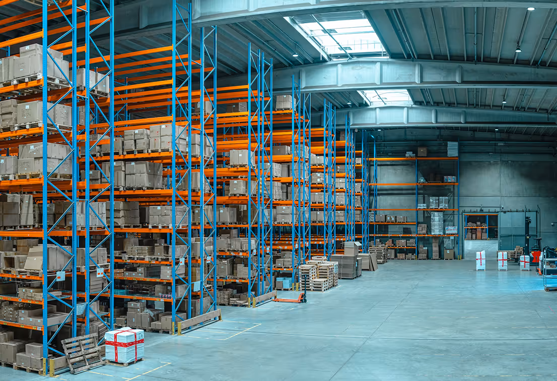 Large warehouse with tall blue and orange racks filled with stacked cardboard boxes.