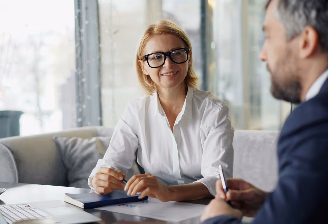 Smiling businesswoman in glasses talking with a man during a meeting in a bright office.