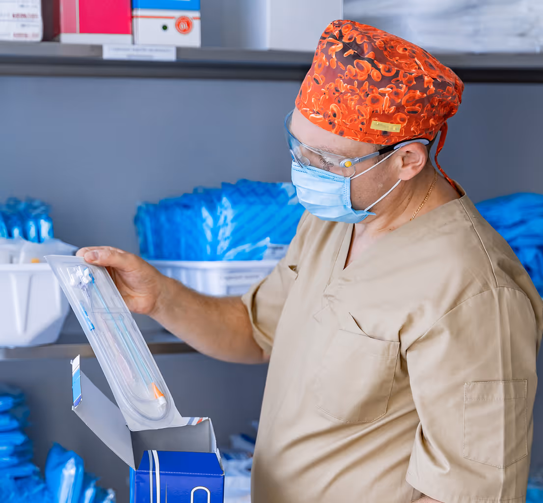 Male doctor and female nurse in scrubs looking at a tablet and smiling in a bright office.