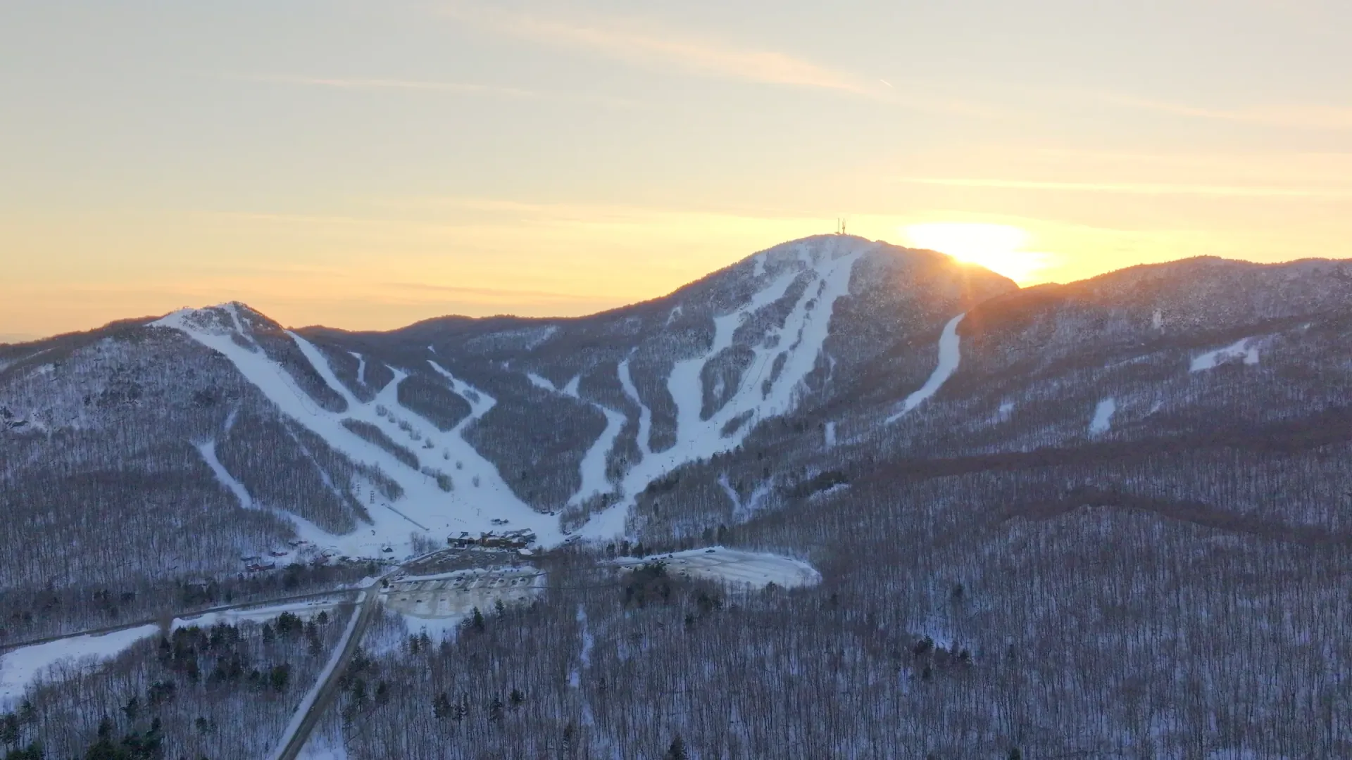 Vue aérienne au drone d'une montagne de ski enneigée au coucher du soleil