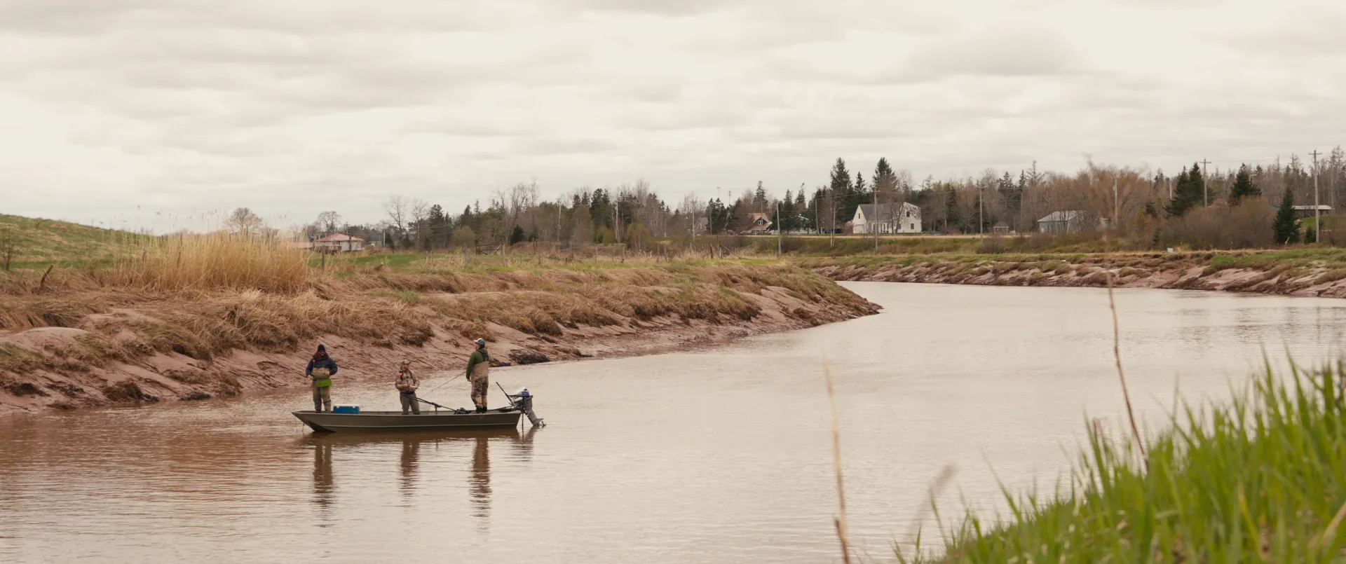 Pêcheurs en cuissardes dans une rivière sous un ciel nuageux, documentaire sur l'art de la pêche