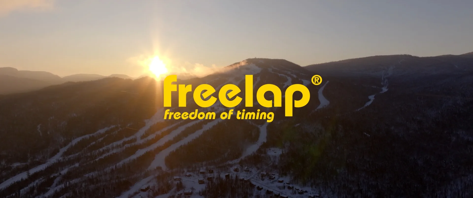 Vue aérienne d'une station de ski enneigée au soleil couchant, avec le logo Freelap en surimpression
