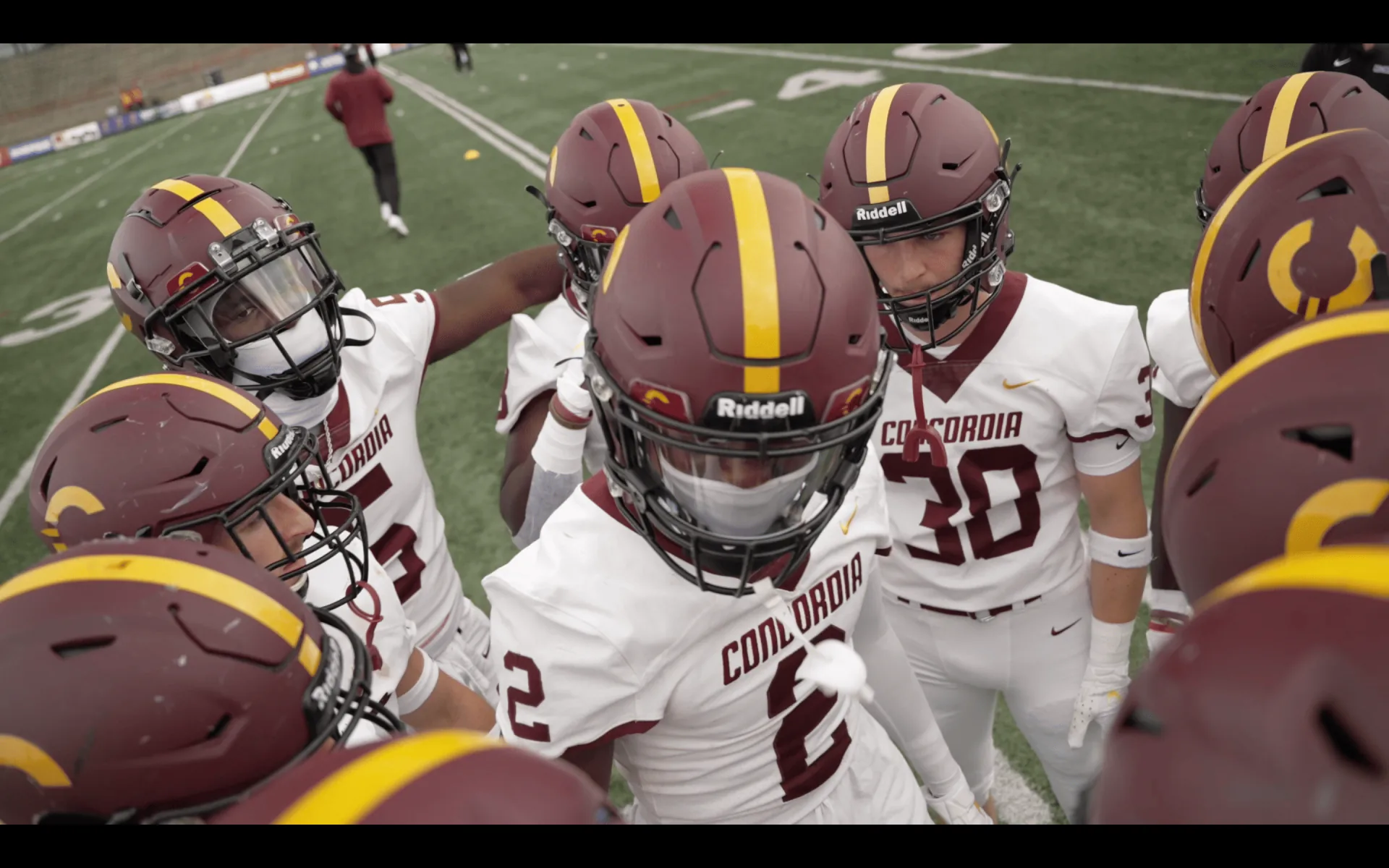 Joueurs de football des Stingers de Concordia rassemblés en caucus sur le terrain avant le jeu