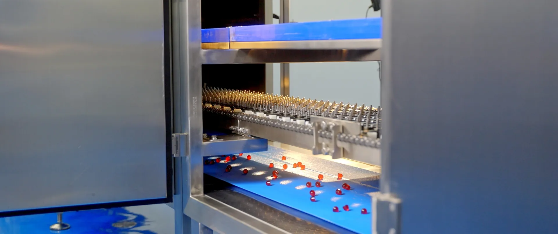 Chaîne de production industrielle en marche, capsules rouges défilant sur un convoyeur en usine