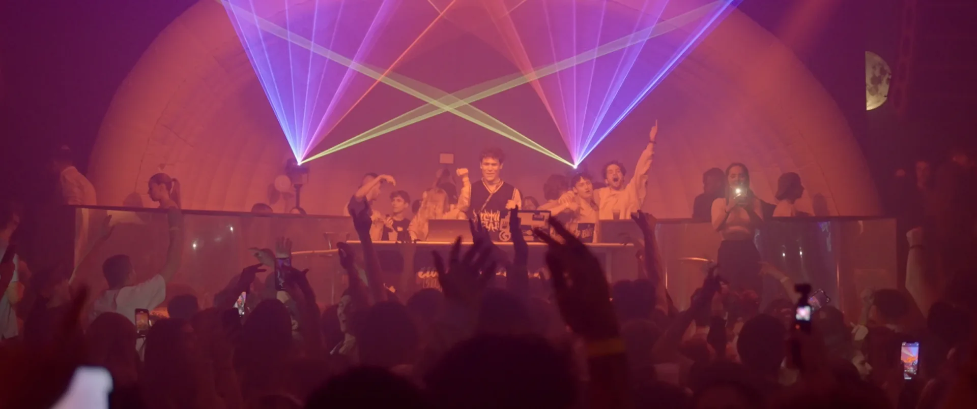 Artiste debout sur une table qui harangue la foule dans une soirée de club aux lumières rouges