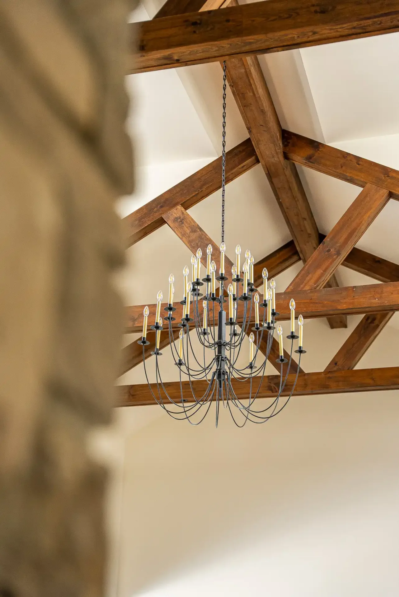 Lustre à bougies suspendu à une charpente de bois apparente
