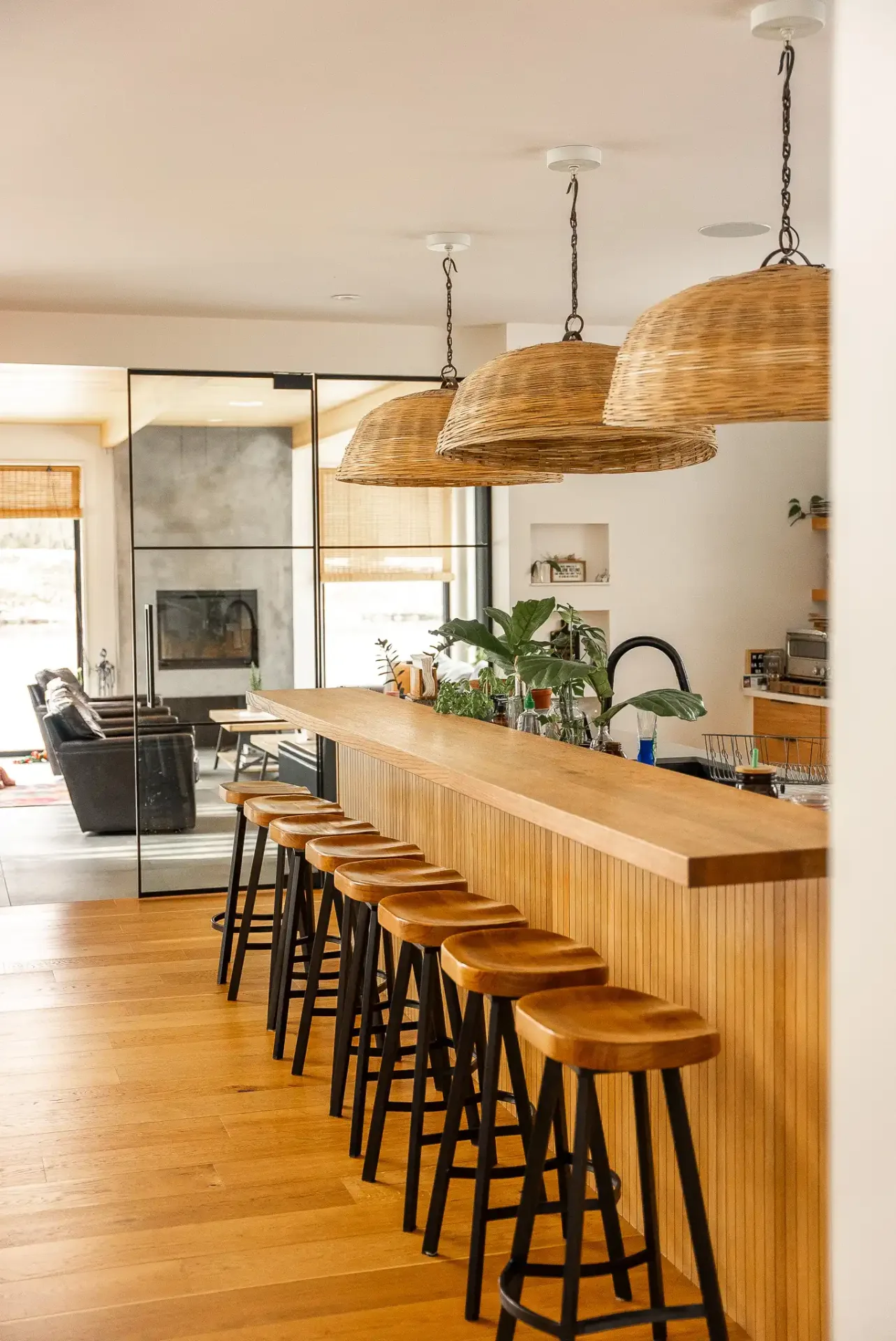 Comptoir-bar en bois et tabourets noirs devant la cuisine