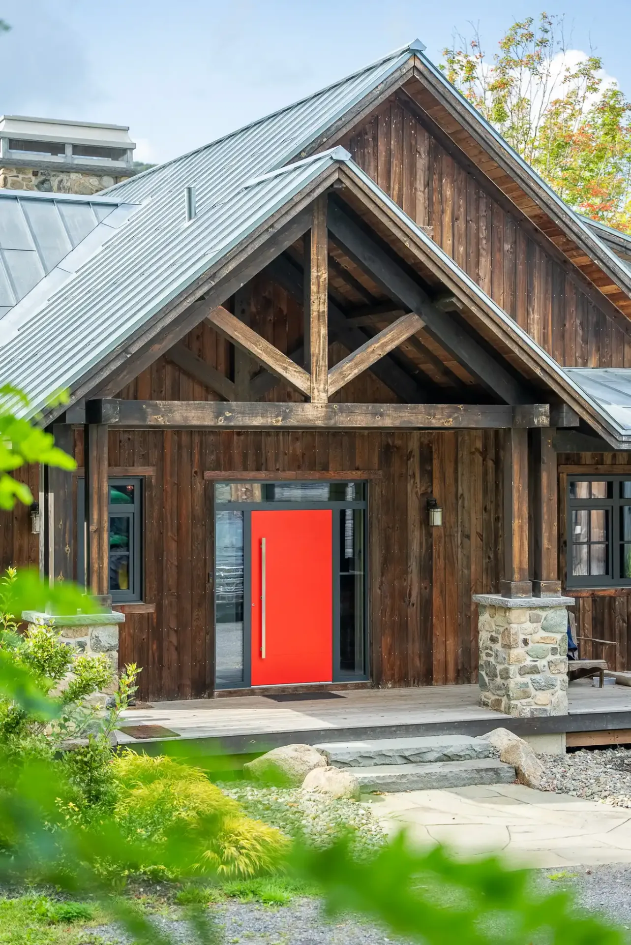 Façade de bois grange et porte rouge sous un pignon de pierre