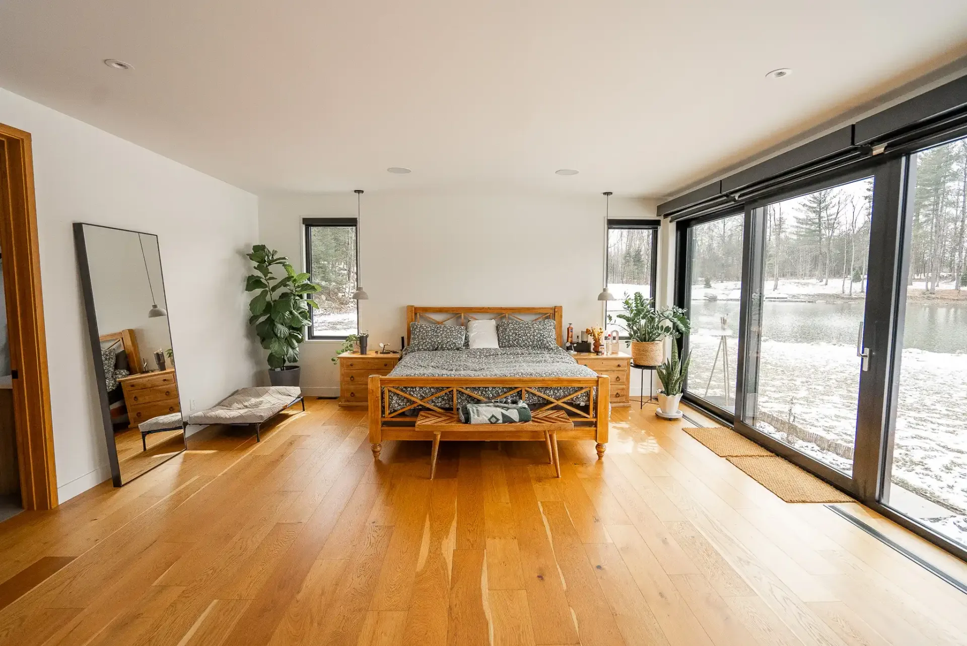 Chambre au lit de bois ouverte sur un paysage enneigé par la baie vitrée