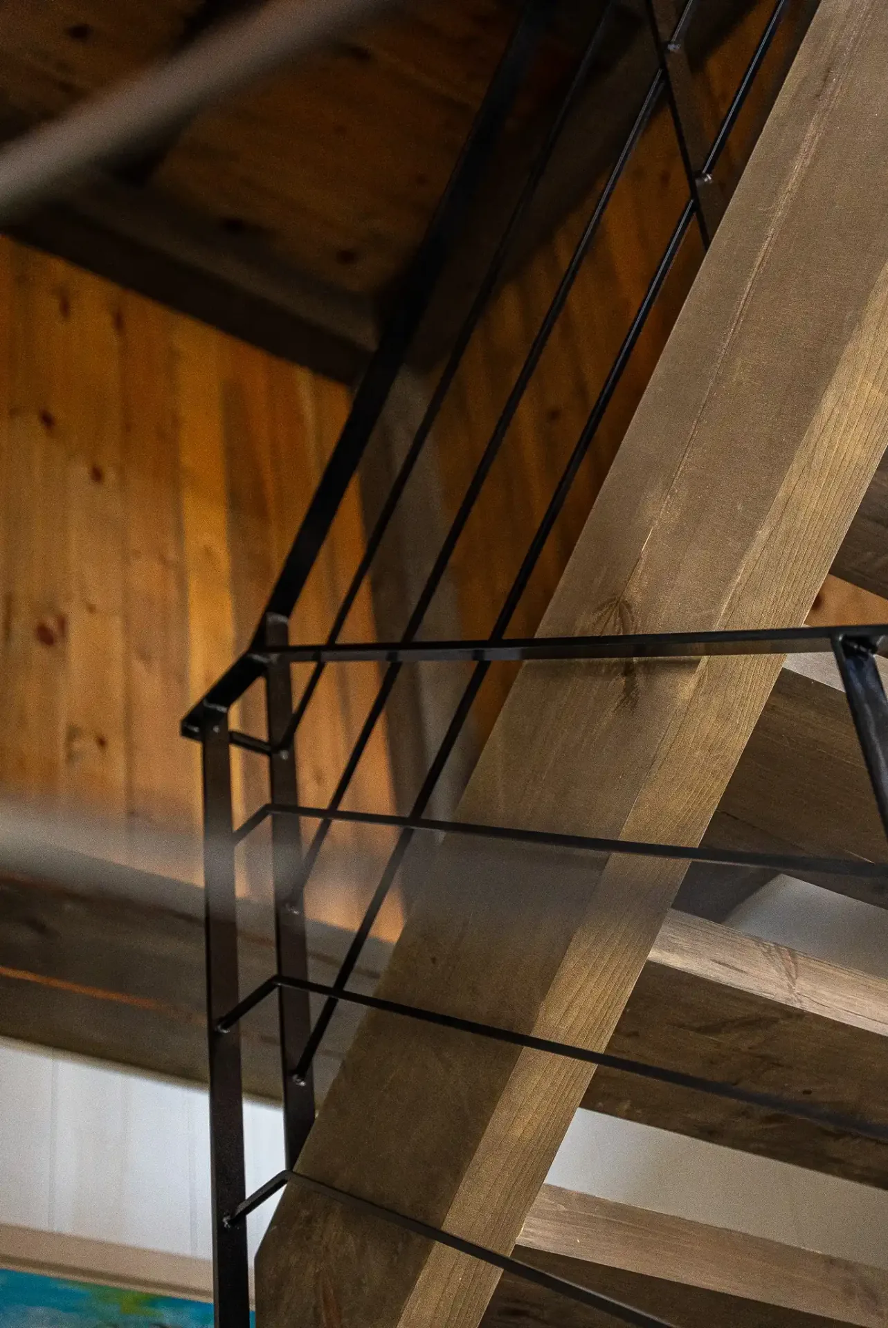 Escalier de bois et garde-corps d'acier noir vus en contre-plongée
