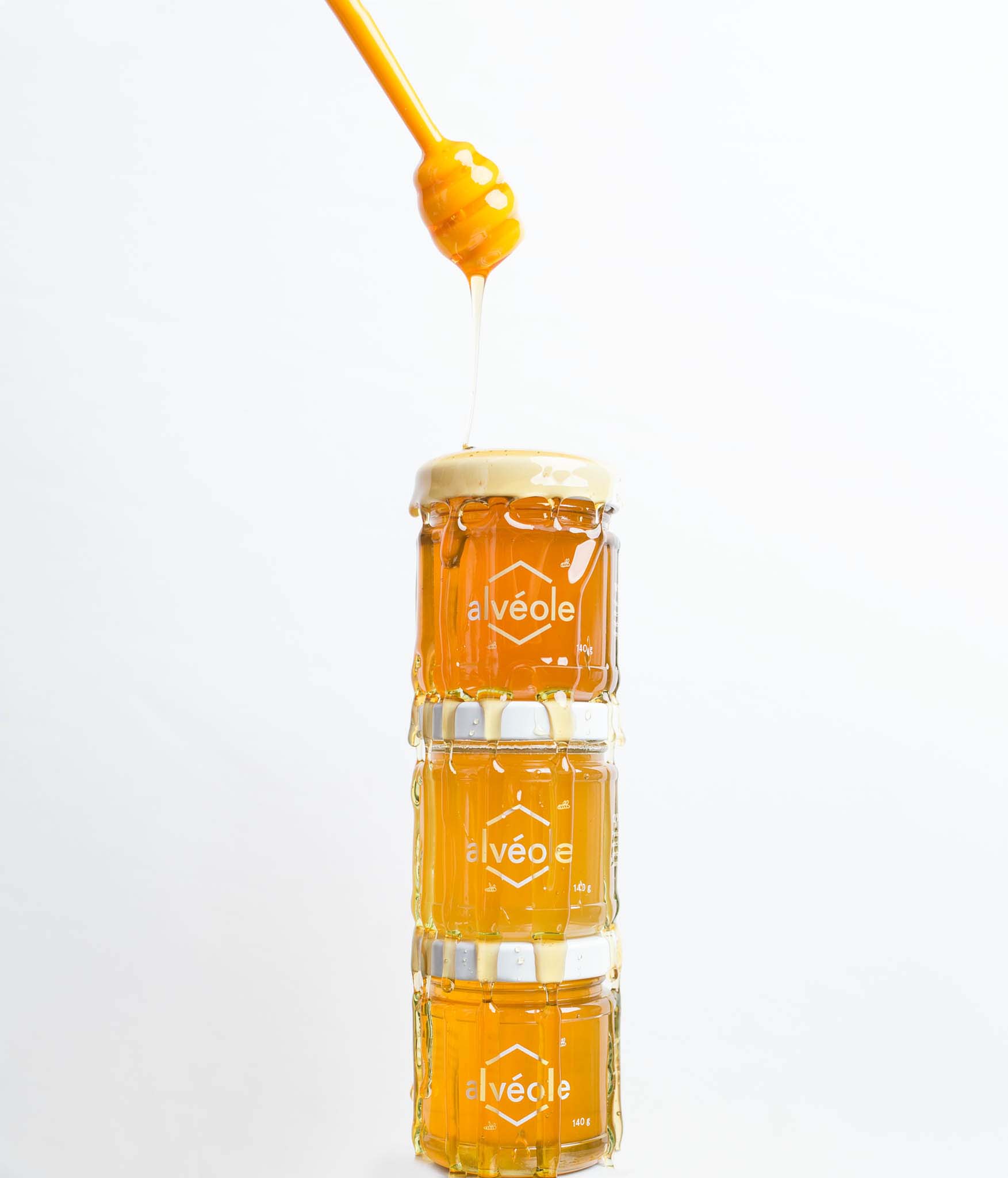 A stack of honey jars dripping with honey.