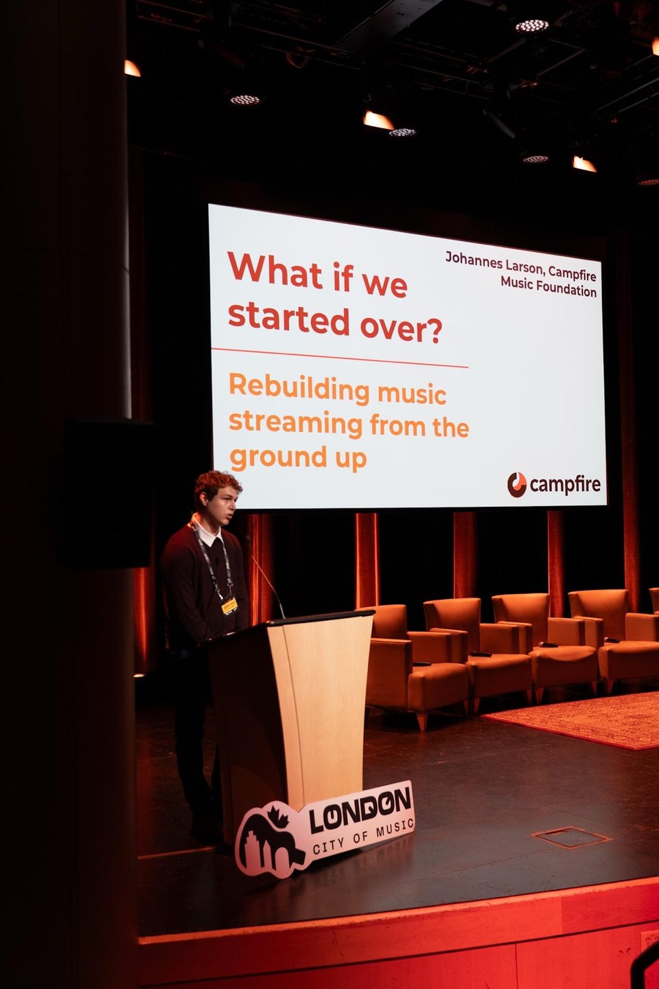 Johannes Larson speaking at a podium marked London City of Music, in front of a slide reading What if we started over? Rebuilding music streaming from the ground up.