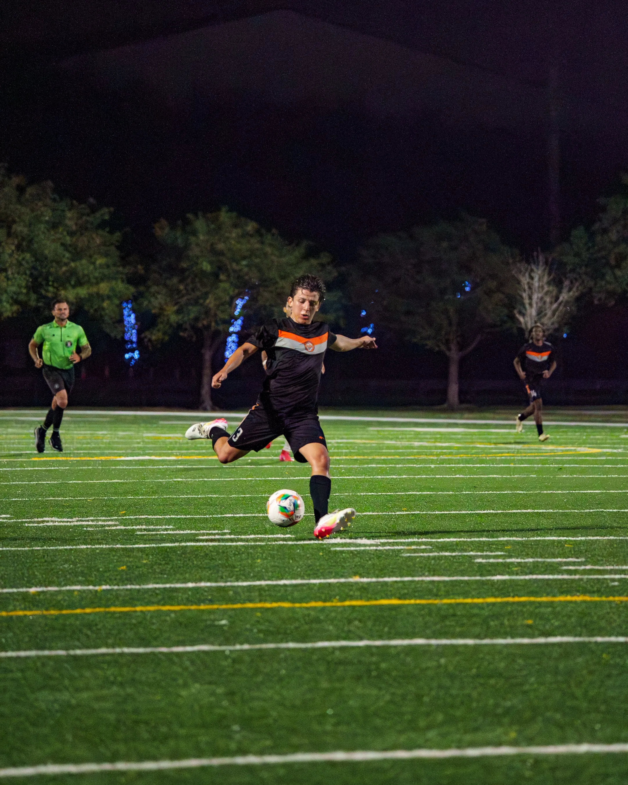 Soccer Paradise FC adult player striking the ball during a night match
