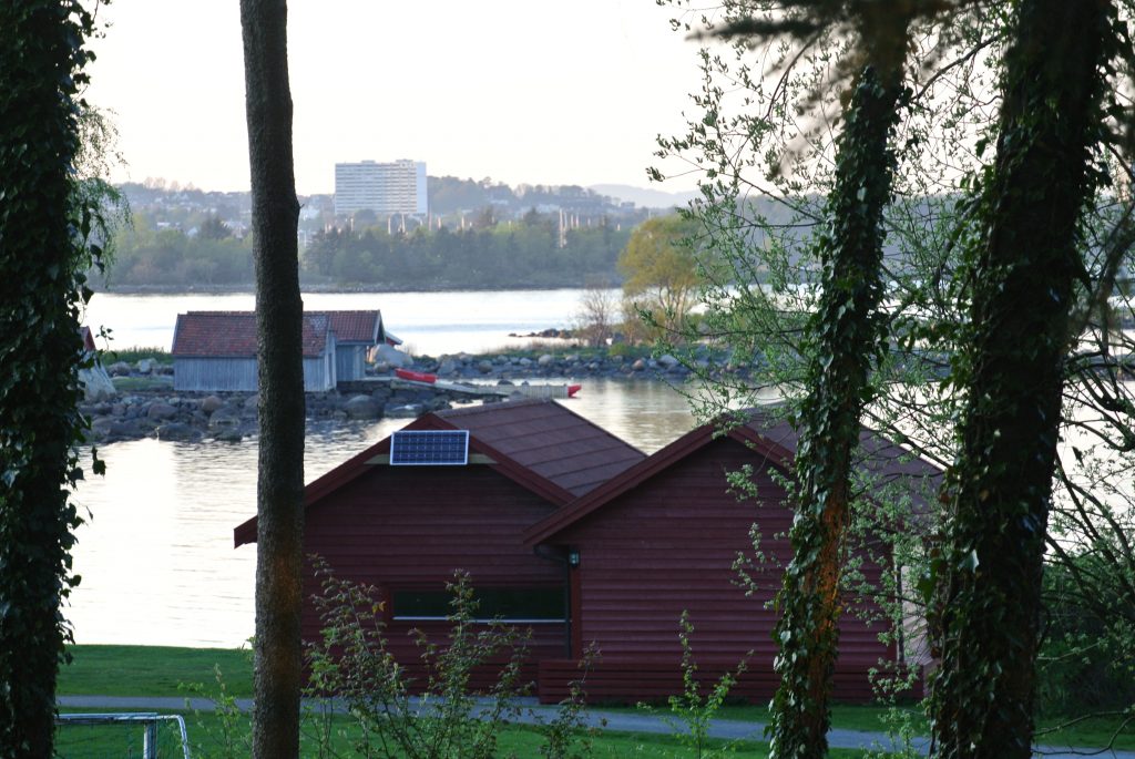 Naustet ved vannet med kajakker på stranden