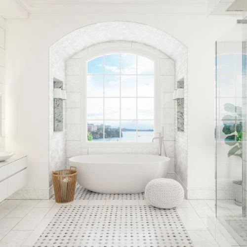Bright white bathroom with freestanding tub, arched window, patterned floor, and glass shower.