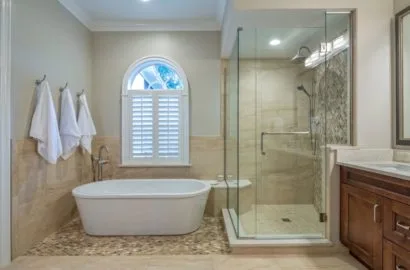 Modern bathroom with a freestanding tub, glass shower, tiled floor, and wooden vanity cabinet.