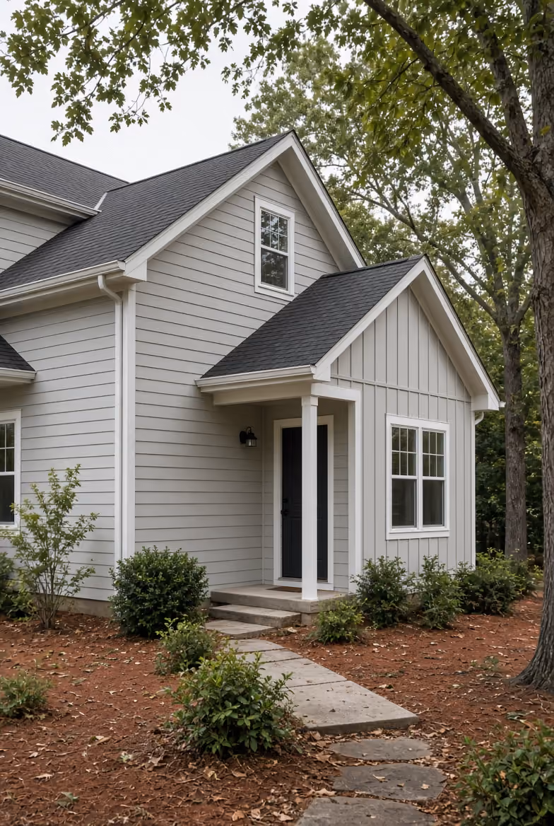 Covered porch with white columns and stone bases overlooking a wooded backyard.