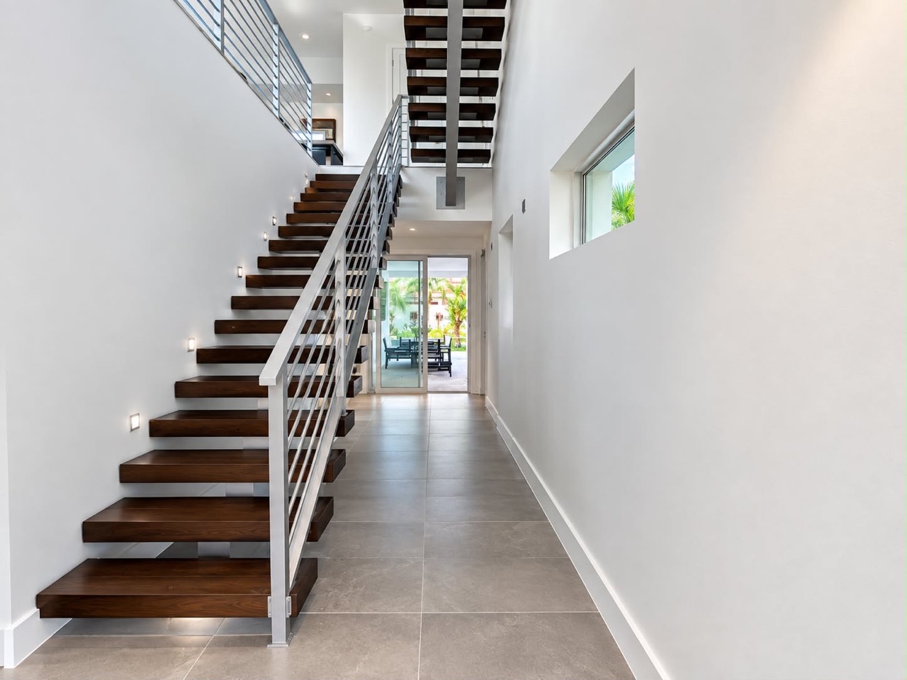 Bright modern interior with freshly painted white walls, floating wood staircase, and metal railing