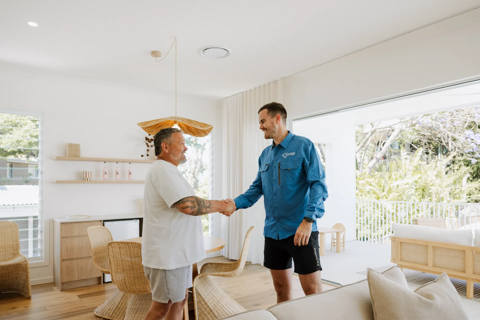 Diamond Air & Energy technician shaking hands with a Brisbane homeowner in a bright living room