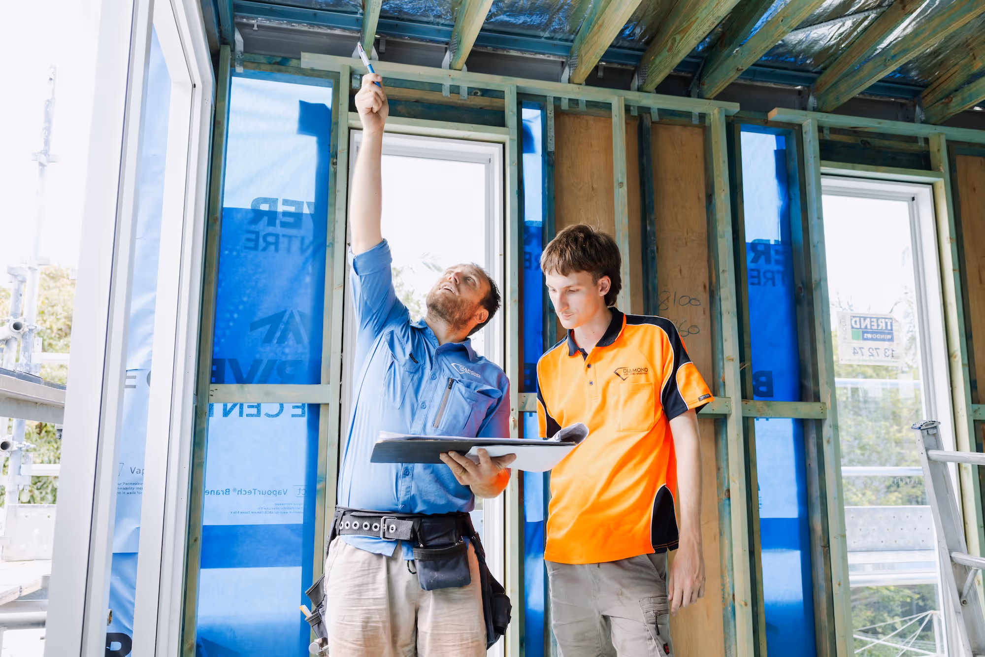 Two construction workers inspecting a wooden frame inside a building under construction.