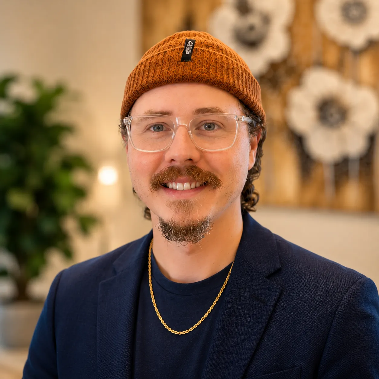 Dalton Patterson, UX-focused digital designer, wearing clear glasses, an orange beanie, and a navy blazer.