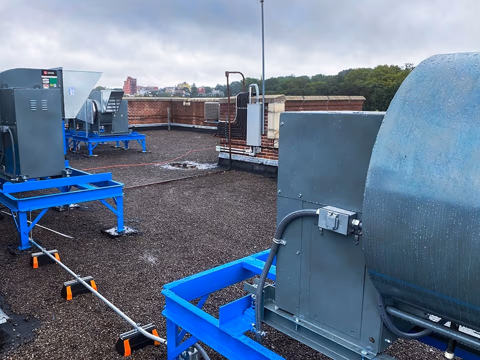 Commercial rooftop installation featuring large building management system control units and emergency ventilation systems set against an outdoor landscape.