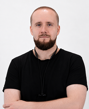 Mężczyzna z krótkimi jasnobrązowymi włosami w dużych czarnych okularach patrzy przed siebie.