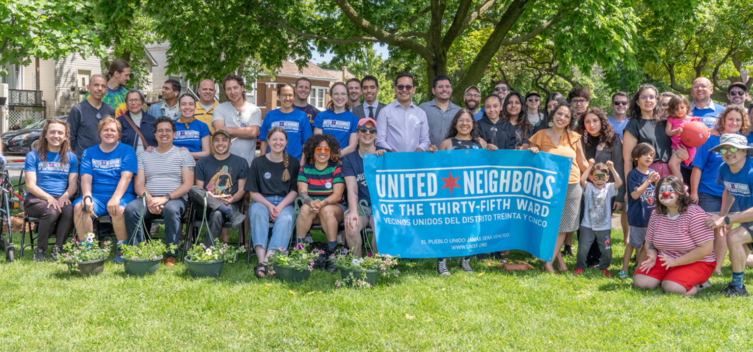 Group of diverse people gathered outside holding a blue banner for United Neighbors of the Thirty-Fifth Ward.